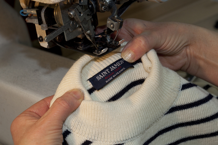 Photographie d'une marinière SAINT JAMES dont le col est mis en place par une couturière à la machine