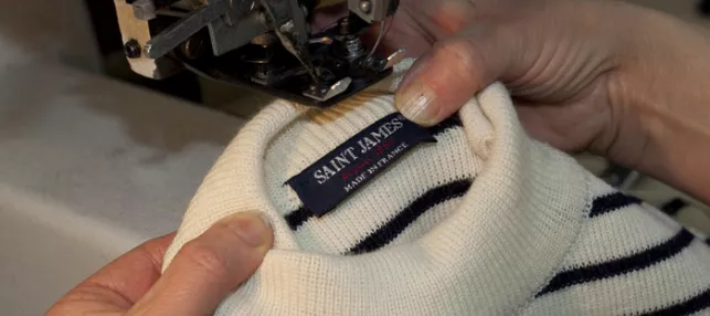 Photographie d'une marinière SAINT JAMES dont le col est mis en place par une couturière à la machine