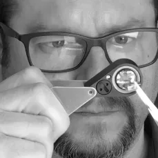 Photo de Cédric Engelaere observant à la loupe une gemme