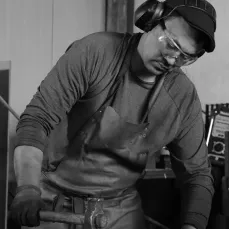 Portrait de Jeremy Roger qui forge une houe