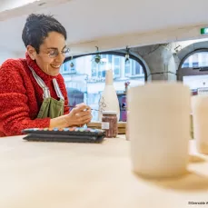 Carine Billard, céramiste de l’Atelier Kaolin à Grenoble, décorant une pièce en grès dans son atelier-boutique.