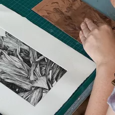 stagiaire qui grave une matrice au burin à côté d'un premier tirage, formation pro