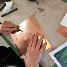 Gravure au burin - formation professionnelle, stagiaire en train de graver sur une plaque de cuivre.