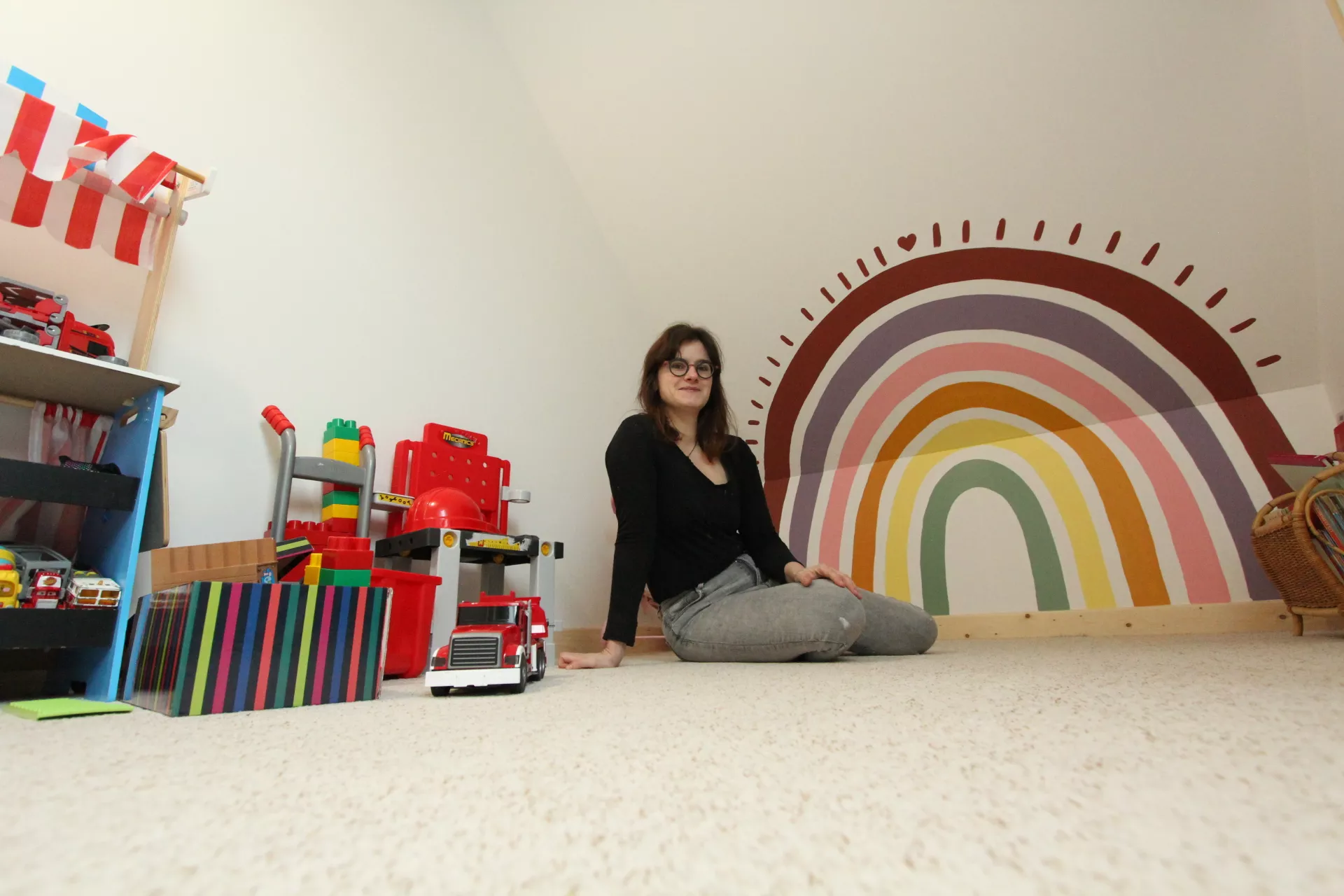 Fresque réalisée sur le mur d'une salle de jeu chez un particulier en Normandie, représentant un arc-en-ciel coloré