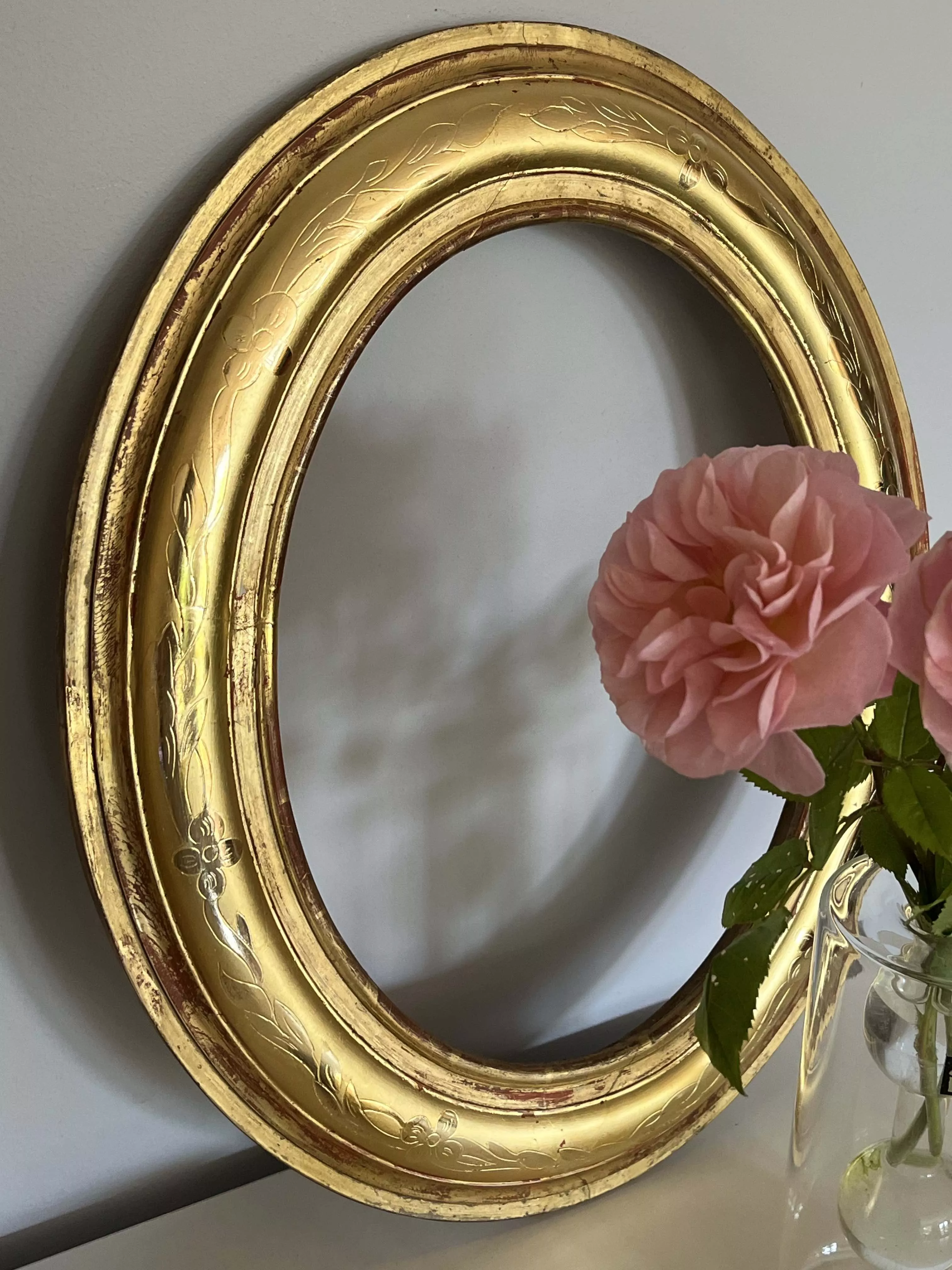 Petit cadre de forme ovale, bombé, en bois doré ancien à décor gravé de guirlandes végétales et florales brillantes sur fond mat. Restauré à la feuille d'or