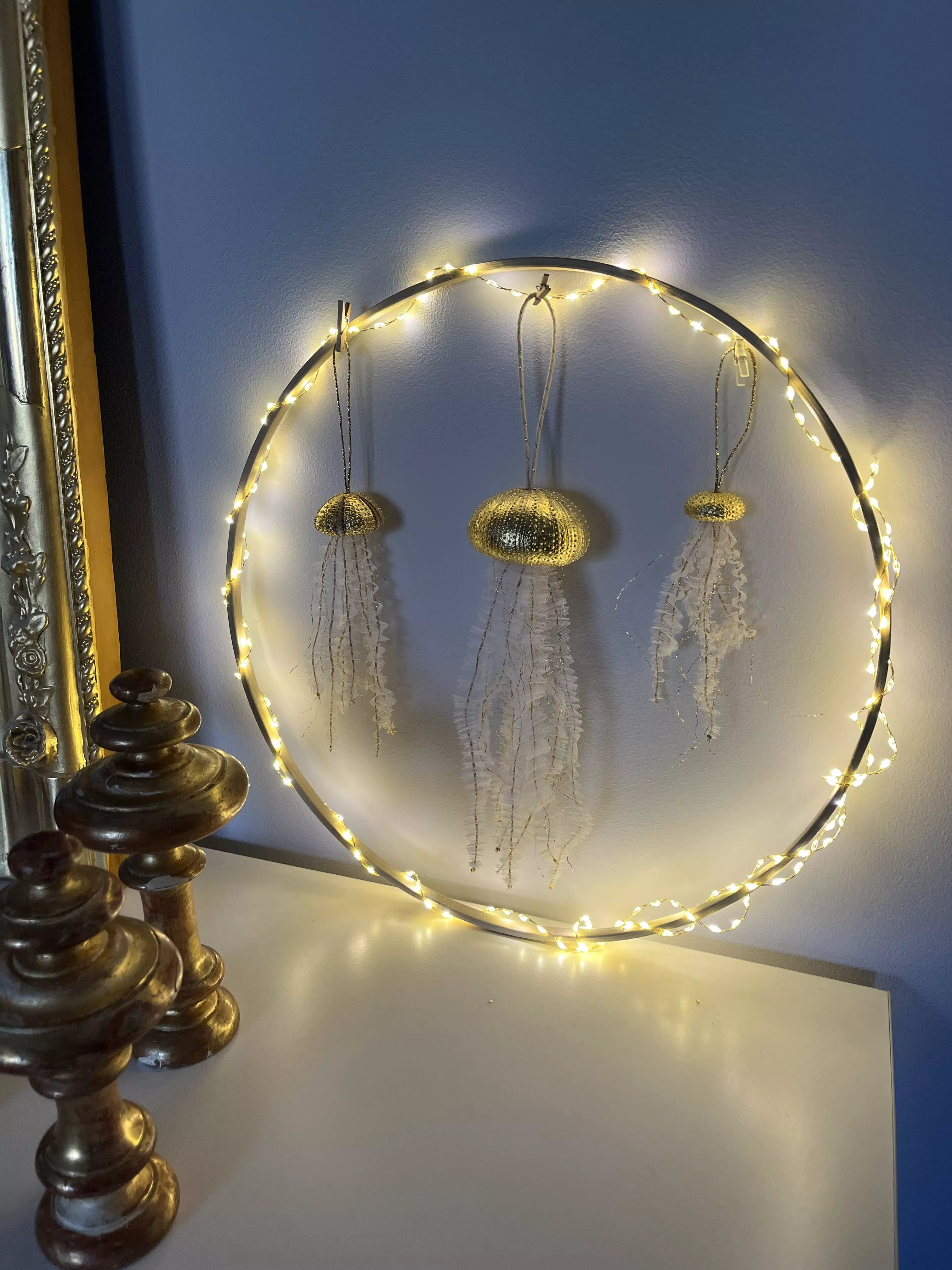 Ensemble de 3 méduses formées d'un oursin doré à la feuille d'or et de tentacules en tulle brodé de fils dorés et plissé; 3 tailles différentes accrochées à un cercle lumineux