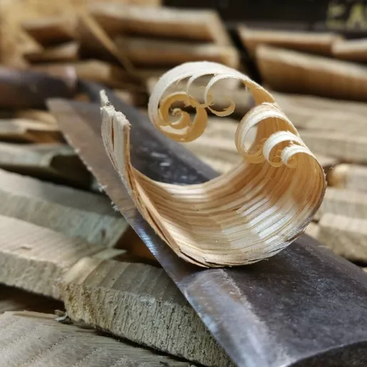 Copeau de châtaignier posé sur un outil de travail du bois nommé plane ou encore couteau à deux manches.