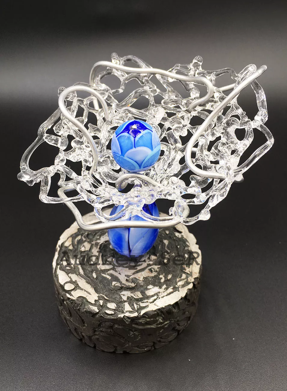 Sculpture verre transparent et opaque bleu lié par un fil métallique.