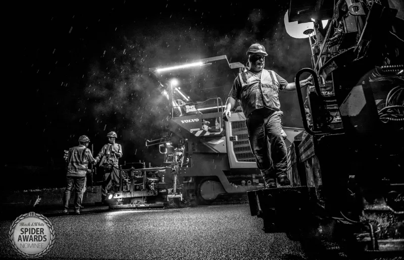 Des hommes travaillant de nuit sous la pluie pour construire une route