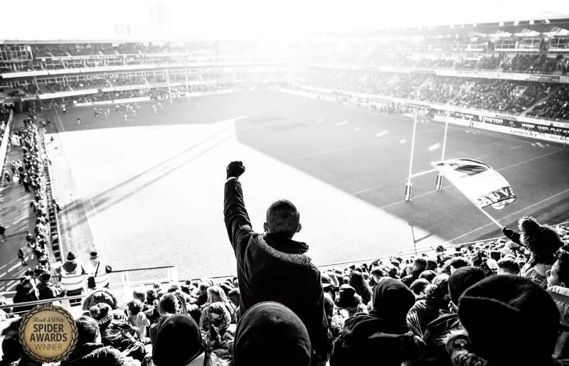 Un enfant se levant le point haut lors d'un match de rugby pour soutenir son équipe