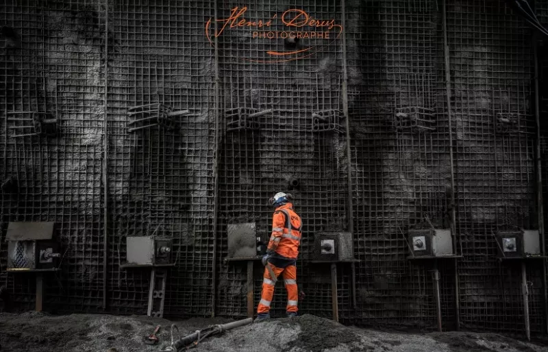 Un homme vêtu en orange en train de construire un pont