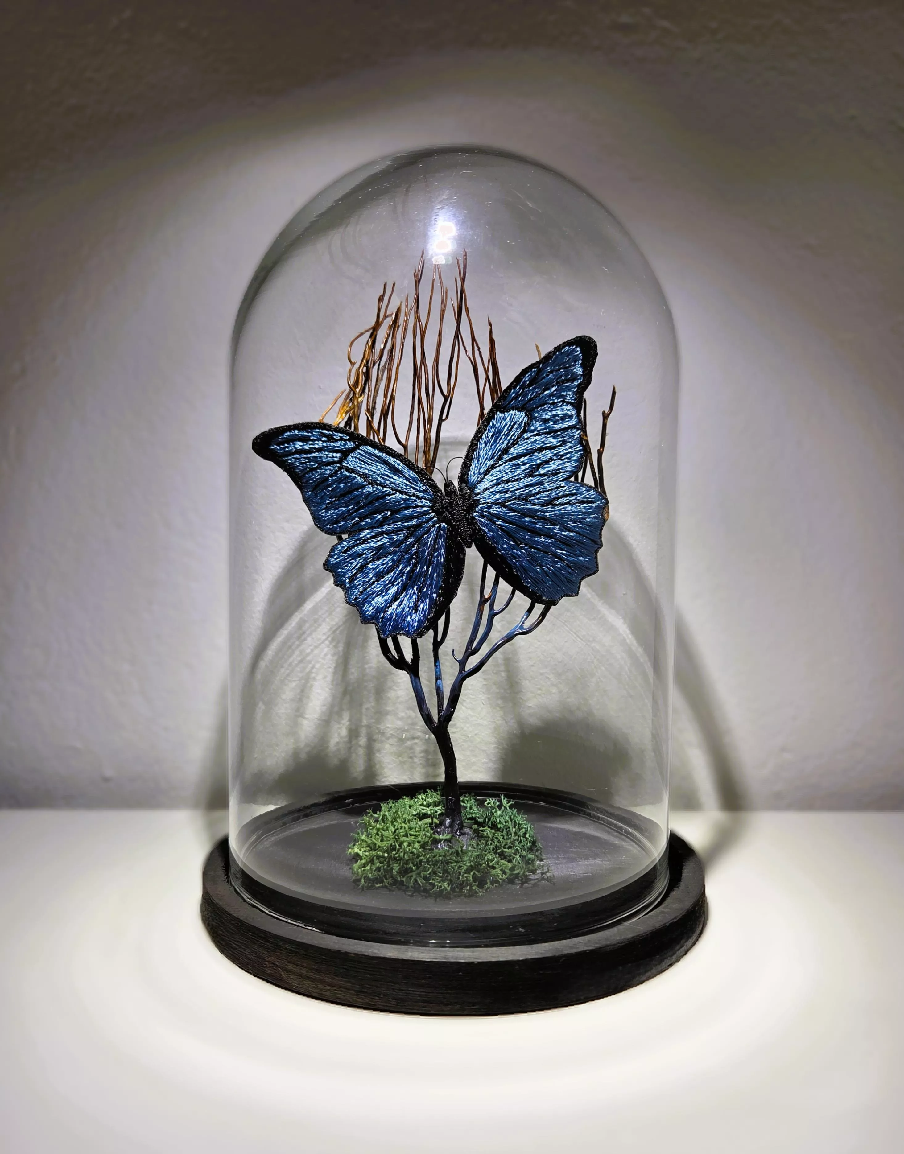 Papillon bleu brodé à la main sous globe