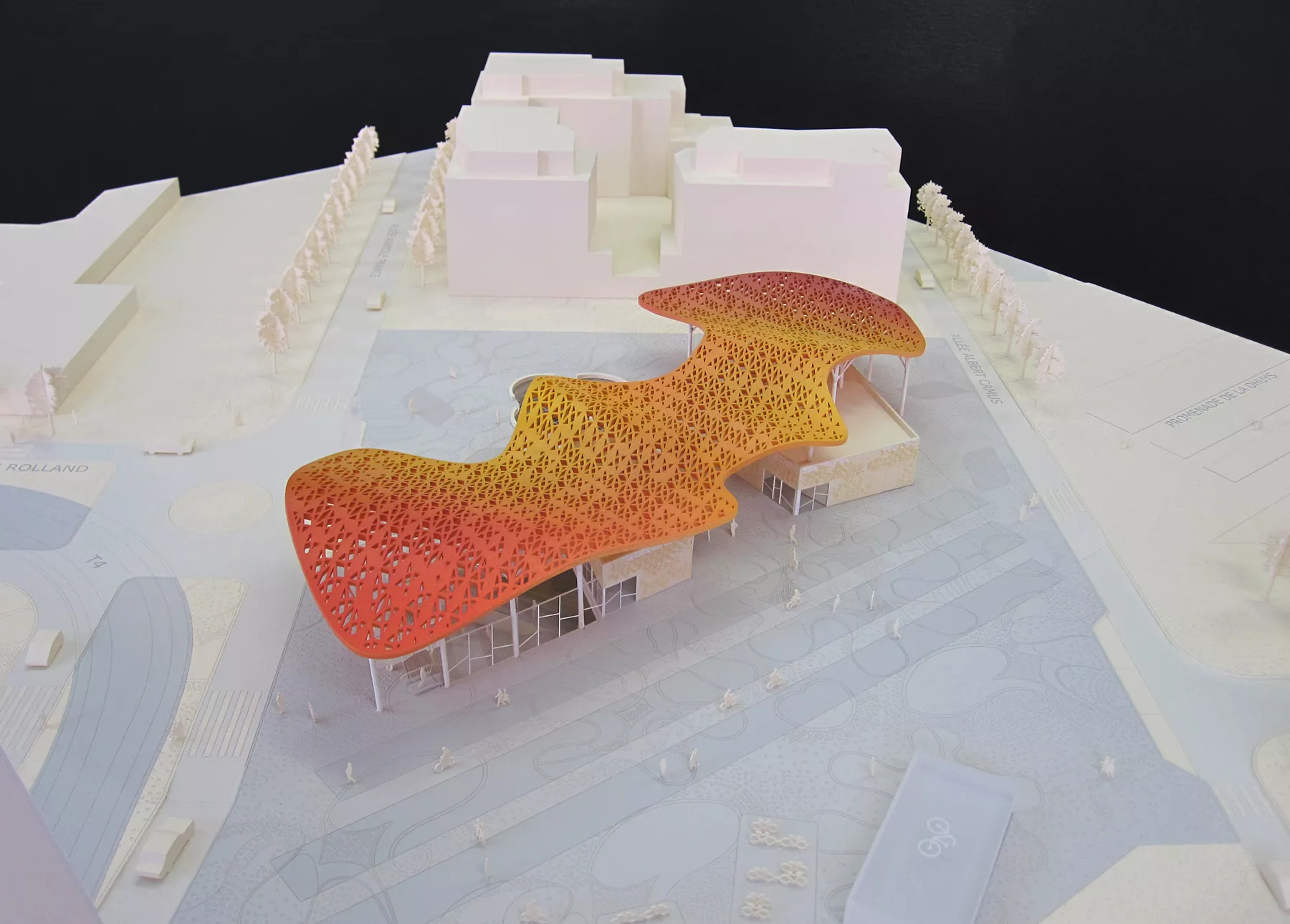 maquette de gare vu légèrement du dessus. Le parvis est gris et la toiture ondulée de la gare ressort avec un dégradé allant de l'orangé au rouge