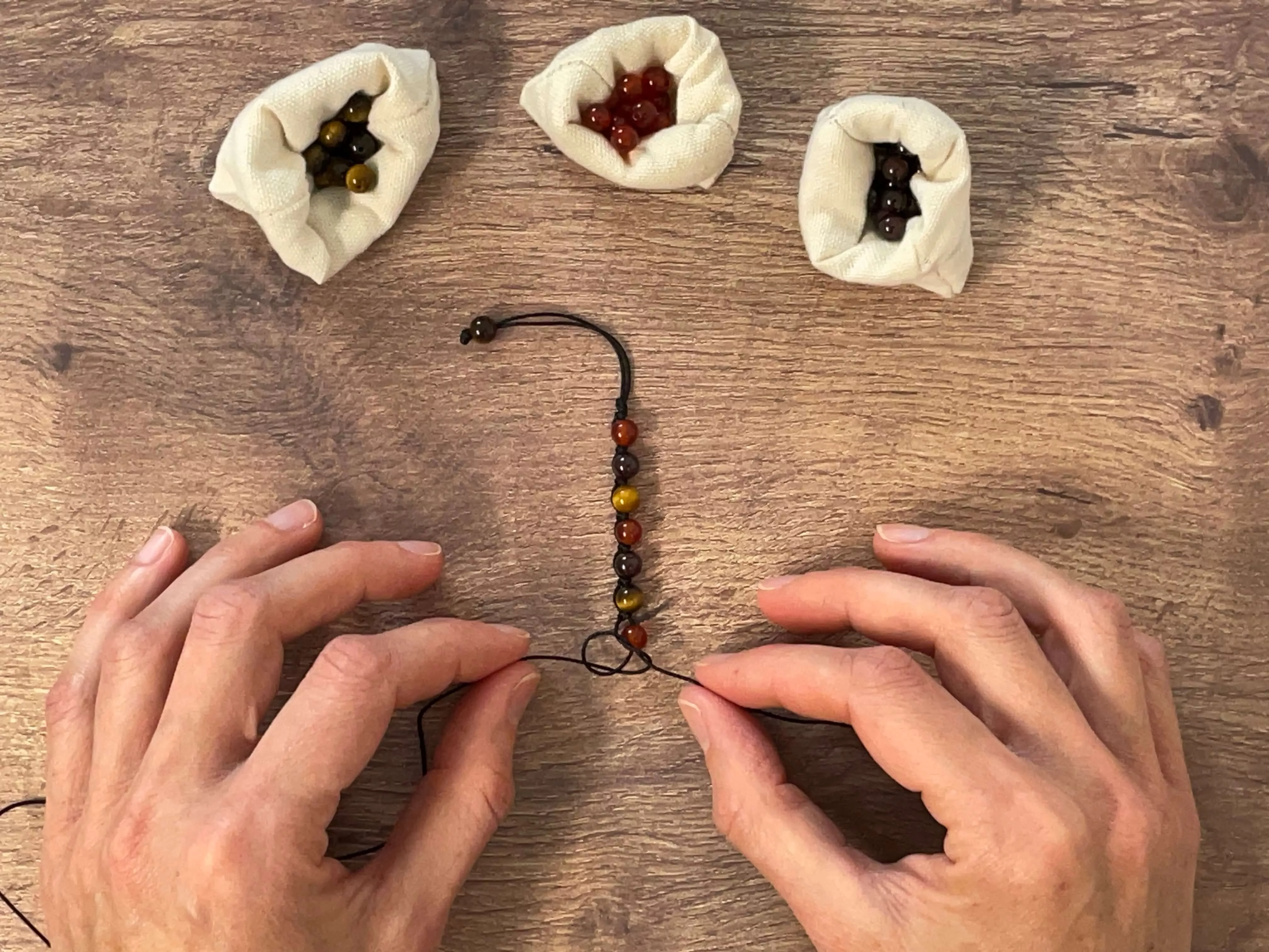 Tressage à la main dans notre atelier d'un bracelet en pierres naturelle sur cordon