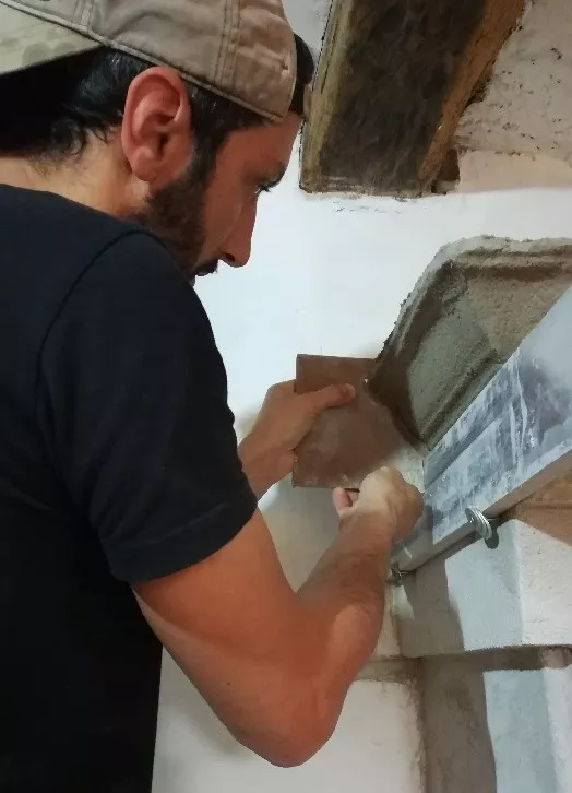 Artisan réalisant une corniche à la chaux à l'aide d'un gabarit