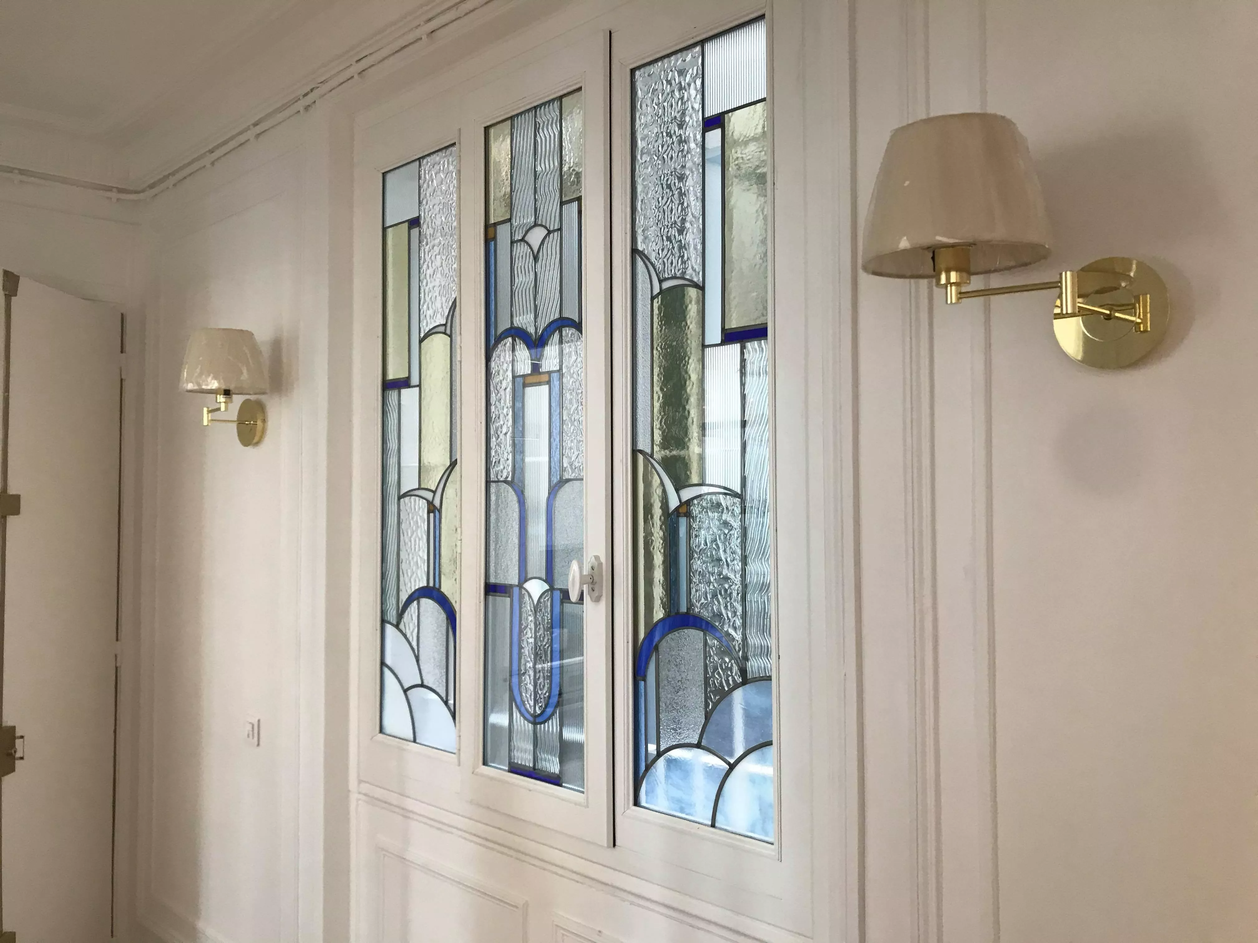 Création de vitrail d'intérieur sur mesure par France Vitrail International, fenêtre à trois battants aux motifs Art Déco en verre teinté et double vitrage.