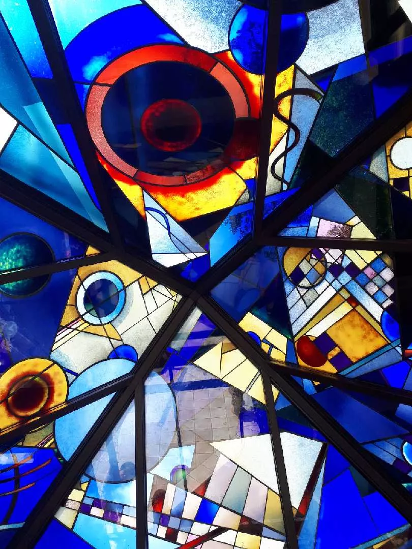 Création sur mesure de plafond en vitrail abstrait contemporain à Paris par France Vitrail International, composition géométrique en verre teinté bleu, rouge et jaune.