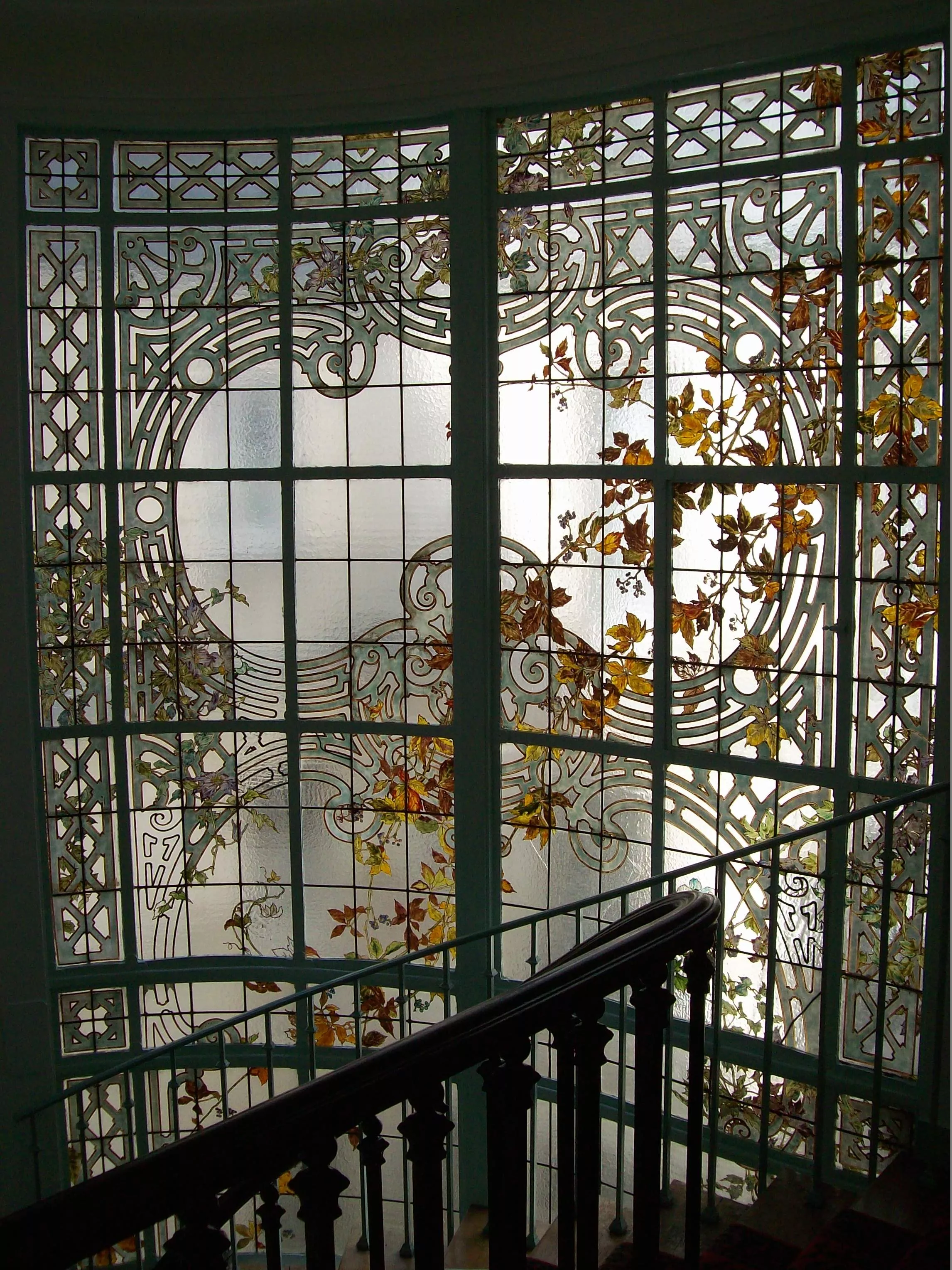 Restauration et rénovation de vitrail d'escalier d'immeuble haussmannien à Paris par France Vitrail International, cage d'escalier en marbre et ferronnerie d'art.