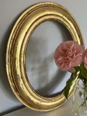 Petit cadre de forme ovale, bombé, en bois doré ancien à décor gravé de guirlandes végétales et florales brillantes sur fond mat. Restauré à la feuille d'or