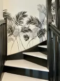 Fresque en noir et blanc dans une montée d'escalier représentant des ombres de feuilles de palmier