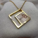 Pendentif carré en laiton doré avec fragment de faïence ancienne à motif floral, monté sur chaîne.