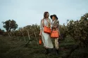 Ballade champêtre dans les vignes d'une mère et sa fille avec leurs sacs De Grimm et un porte-bouteille double