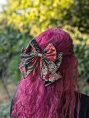 Nœud pour cheveux japonais noir, rouge et doré à motifs floraux et vagues, porté sur une coiffure semi-attachée.