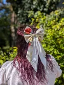 Grand nœud japonais blanc à motifs de grues et fleurs rouges, porté sur cheveux longs en demi-queue.