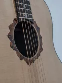 Détail d’une guitare Grand Auditorium mettant en valeur une rosace figurative en marqueterie, inspirée des reliefs montagneux. Les différentes essences de bois sont découpées puis assemblées pour créer un paysage aux nuances et aux profondeurs naturelles. Des repères de touche en forme d’edelweiss prolongent cette identité alpine et établissent une continuité visuelle entre la table et le manche.