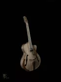 Archtop traditionnelle réalisée entièrement à partir de bois locaux : table sculptée en épicéa alpin, éclisses en noyer et autres éléments principaux en frêne. L’instrument est intégralement fini au vernis au tampon, appliqué en couches fines afin de préserver et révéler le caractère naturel des essences. Son amplification sur mesure associe un micro magnétique dissimulé sous la touche à quatre capteurs piézoélectriques, avec des volumes indépendants.