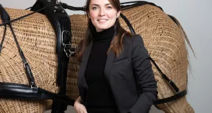 Alice Dauer posant devant sa création, un harnais de dressage équin