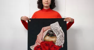 Étudiante en tapisserie de lice posant avec son œuvre