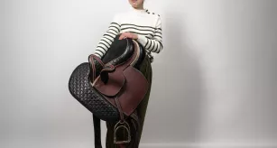 Camille Pierson, étudiante en sellerie-harnachement, posant avec son œuvre, "Fémininité géométrique", une selle d'amazone