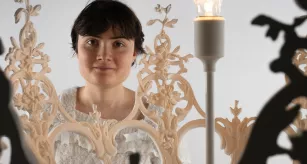 Léana Clabaut, étudiante en BMA volumes, staff et matériaux aossicés, posant avec son œuvre, le luminaire Eidôlon