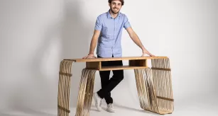 Joseph Clément, étudiant en ébénisterie, posant avec son œuvre, le bureau Phyllo