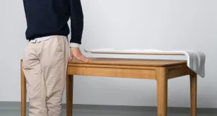 Yohan Thomas, étudiant en ébénisterie, posant devant son œuvre Artizan, un bureau 